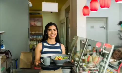 Smiling employee with lunch tray at a modern office cafeteria counter